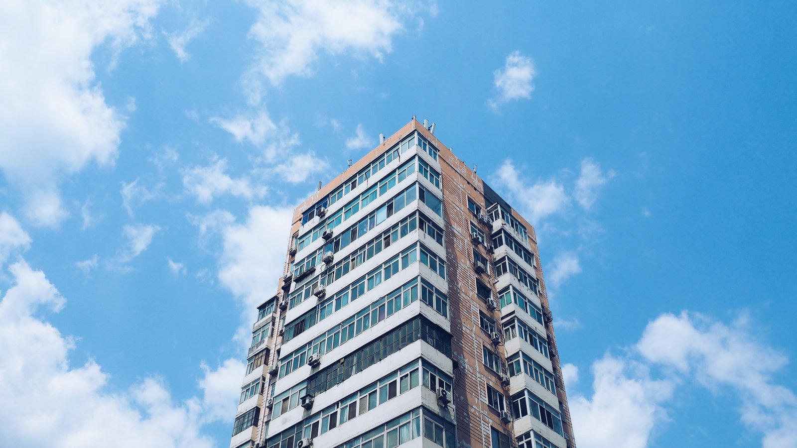 Fachada de un edificio de apartamentos en altura, visto desde abajo contra un cielo despejado (imagen genérica, sin dirección identificable)