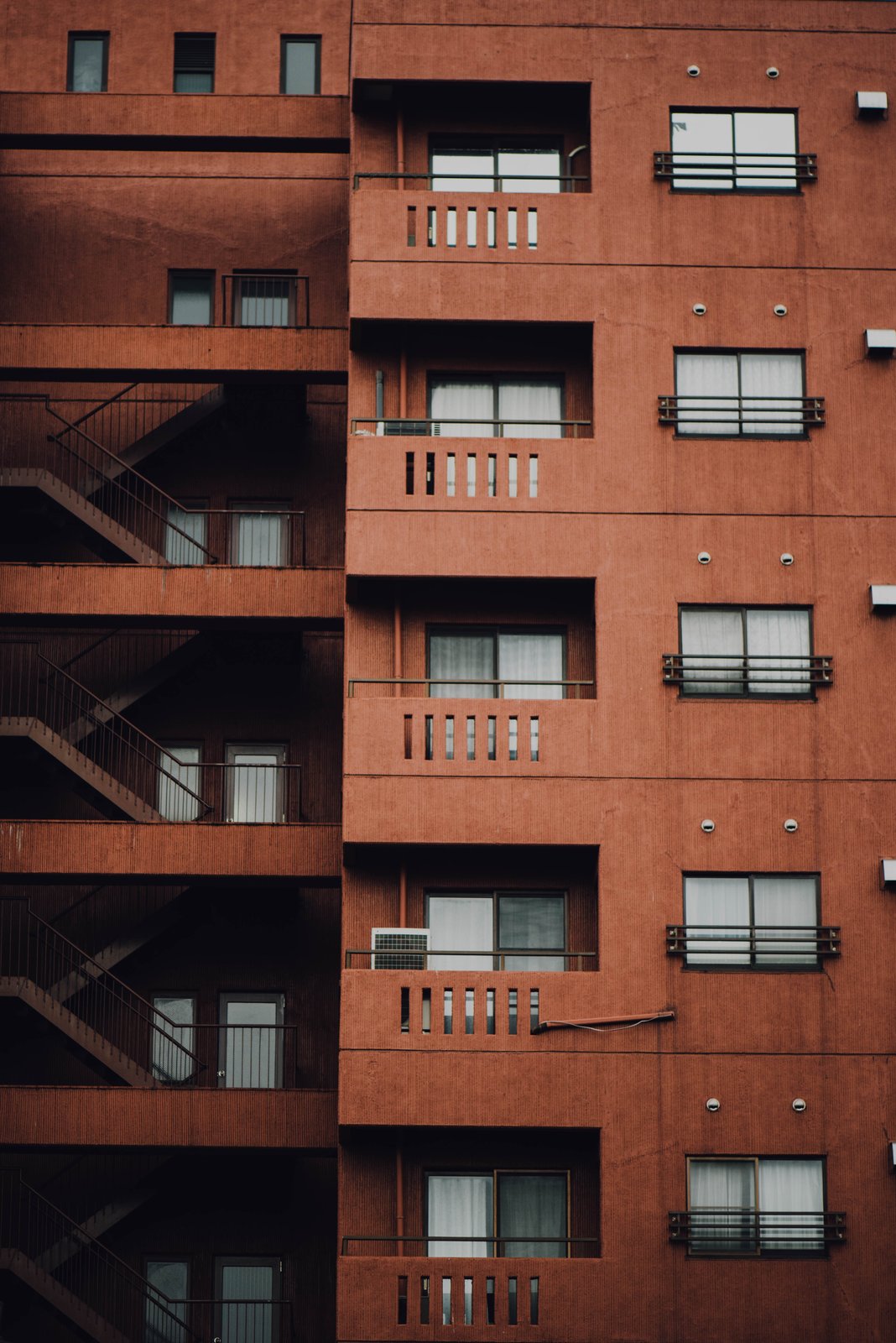 Fachada de un edificio de apartamentos con balcones, escaleras y ventanas (imagen genérica, sin dirección identificable)