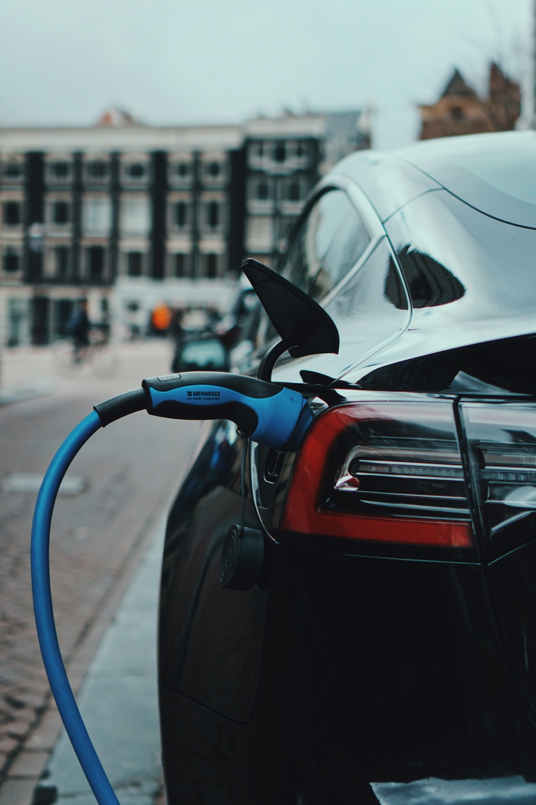 Auto eléctrico cargando con cable Mennekes Tipo 2 en una calle de una ciudad europea